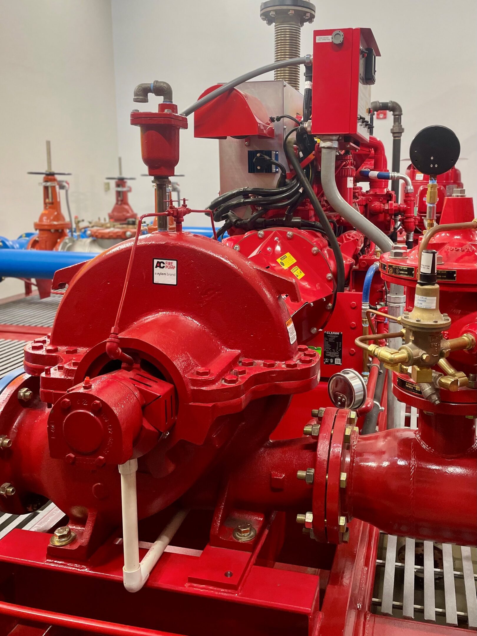Pump A red fire hydrant sitting next to pipes.