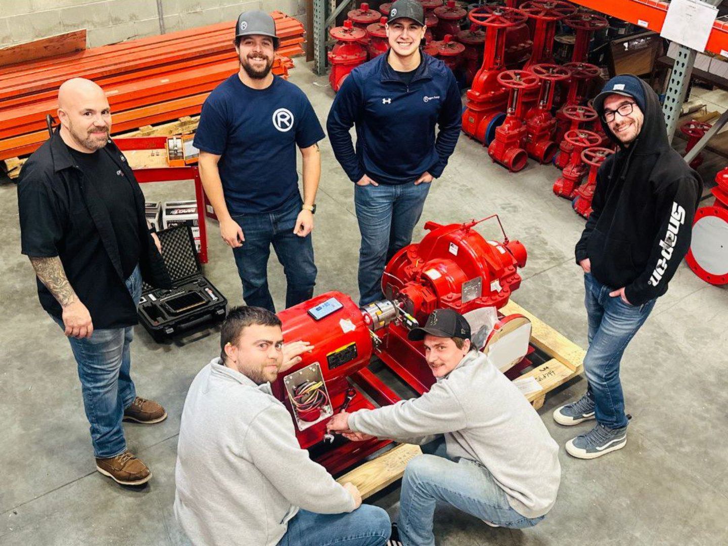 A group of men standing around a red machine.