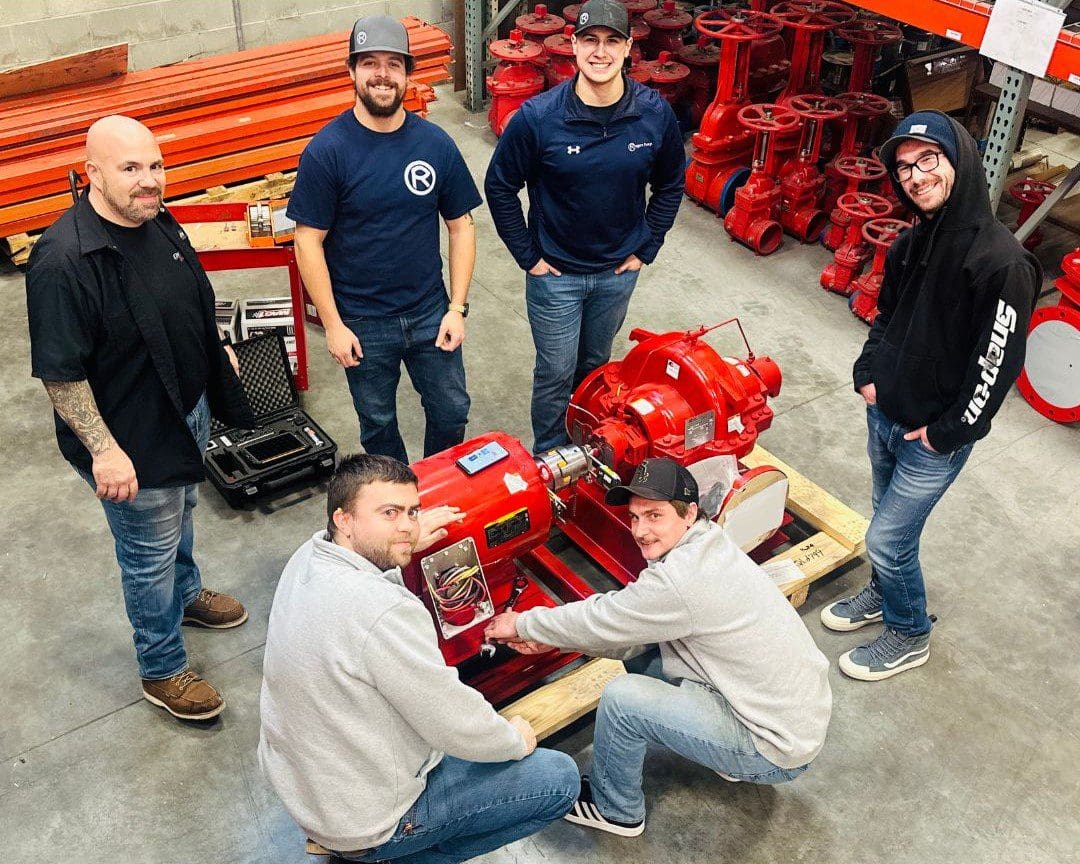 A group of men standing around a red machine.