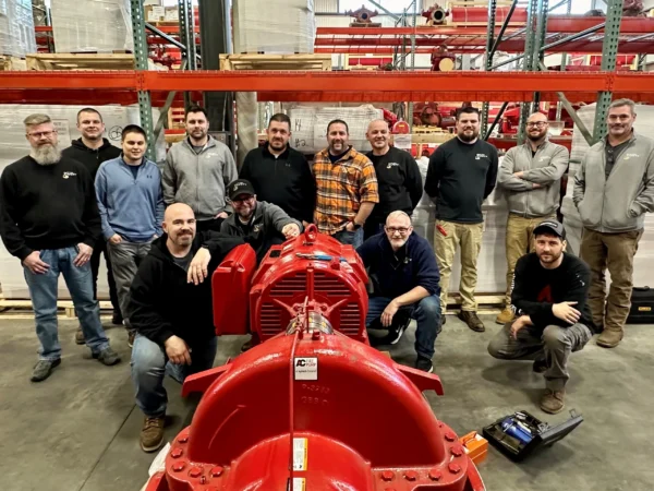 A group of men standing around a red fire hydrant.