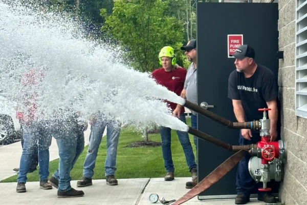 A group of people standing around spraying water on something.