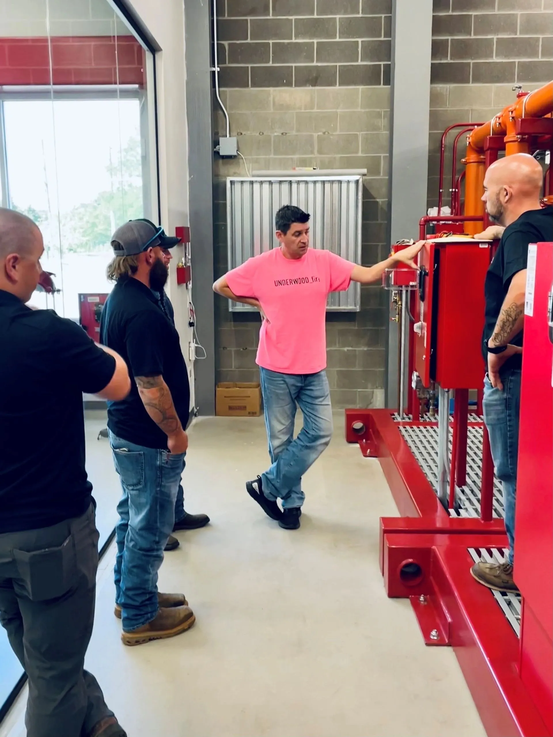 A group of people standing around in front of some pipes.